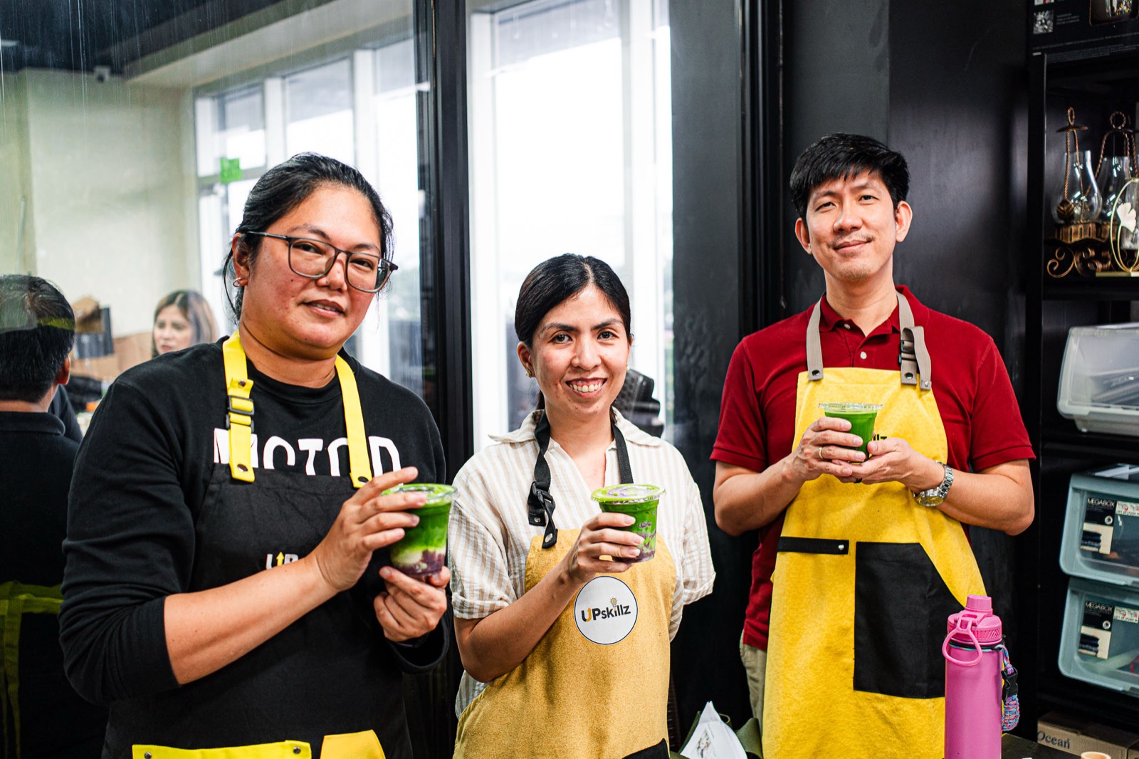Three guests in aprons smiling and holding the matcha they made at a class