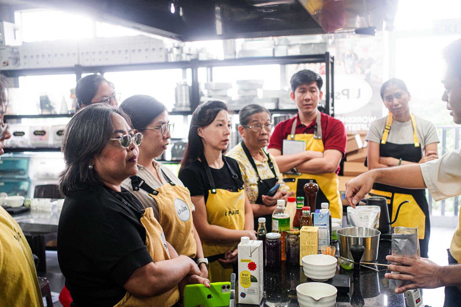 Guests in aprons side by side at a long table, making matcha together