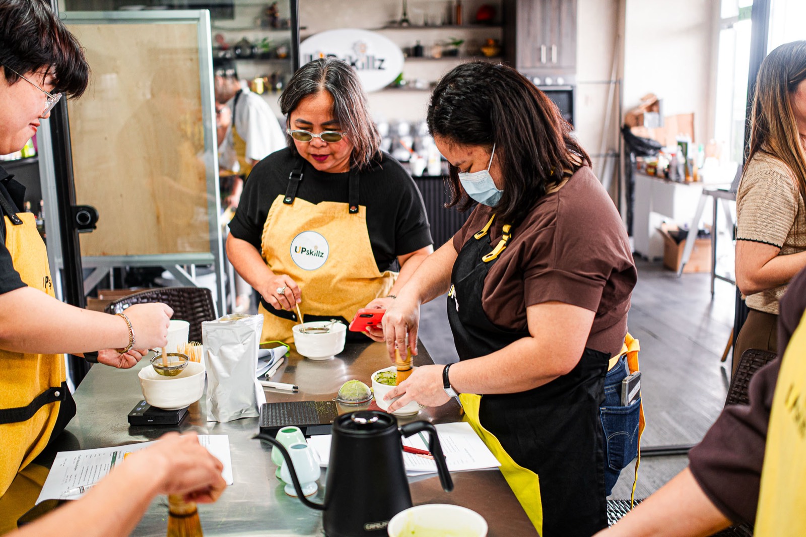 Two guests whisking matcha in bowls at a class